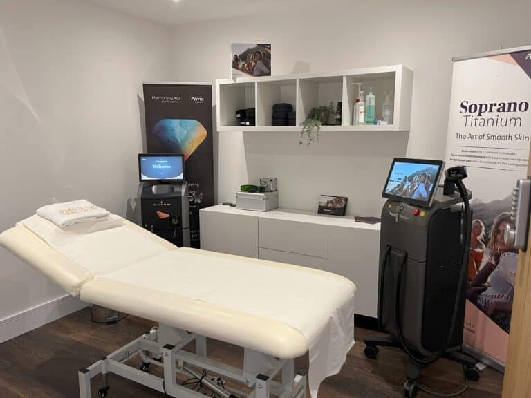 a laser treatment room with a white treatment bed and two laser machines in a clinic in hertfordshire