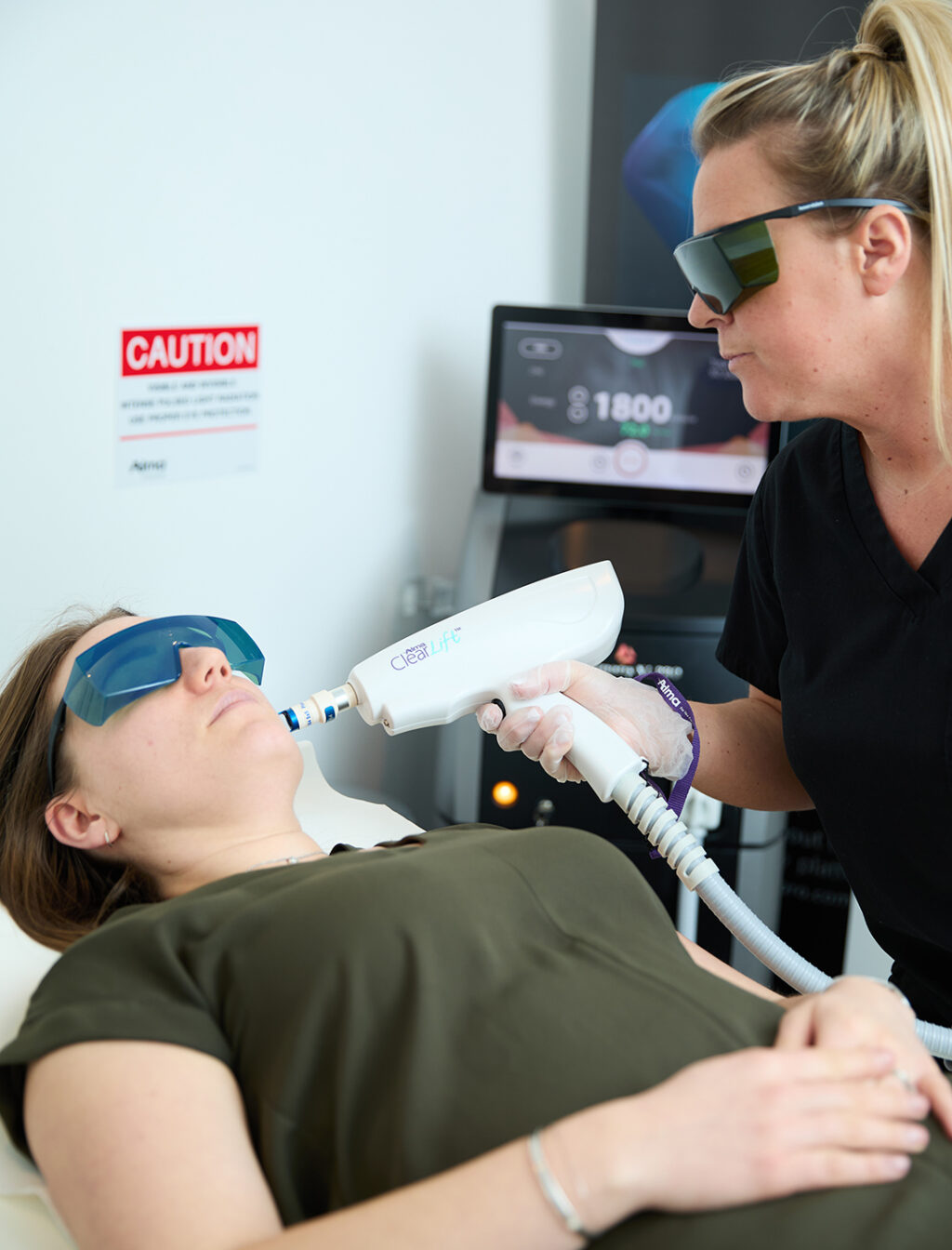 a female is having a laser facial performed by a therapist at Aqua Tox Wellness Clinic in Hertford. They are both wearing blackout safety goggles