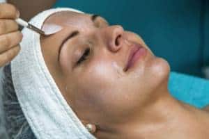 a chemical peel solution is brushed onto a female face